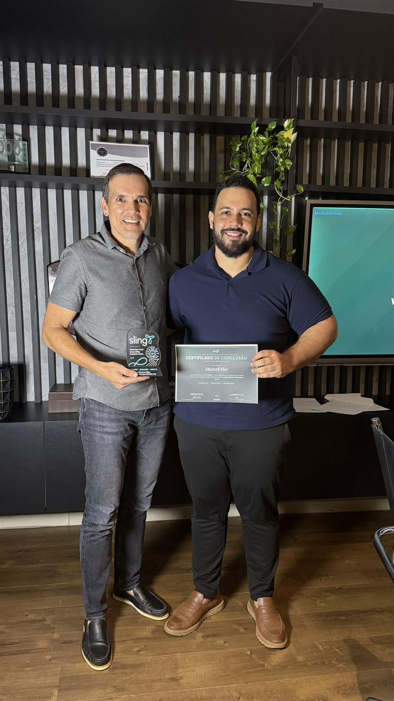 Participante e mentor lado a lado, um segura o troféu de acrílico e o outro o certificado de conclusão
